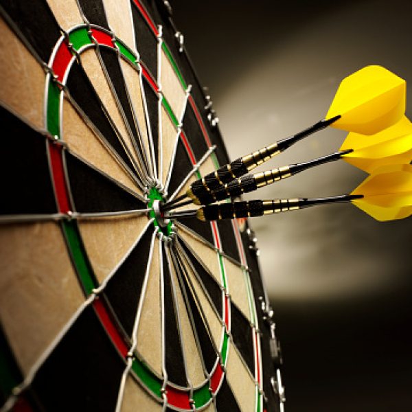 Three yellow darts hitting the target in a game of darts scoring a bulls eye.
